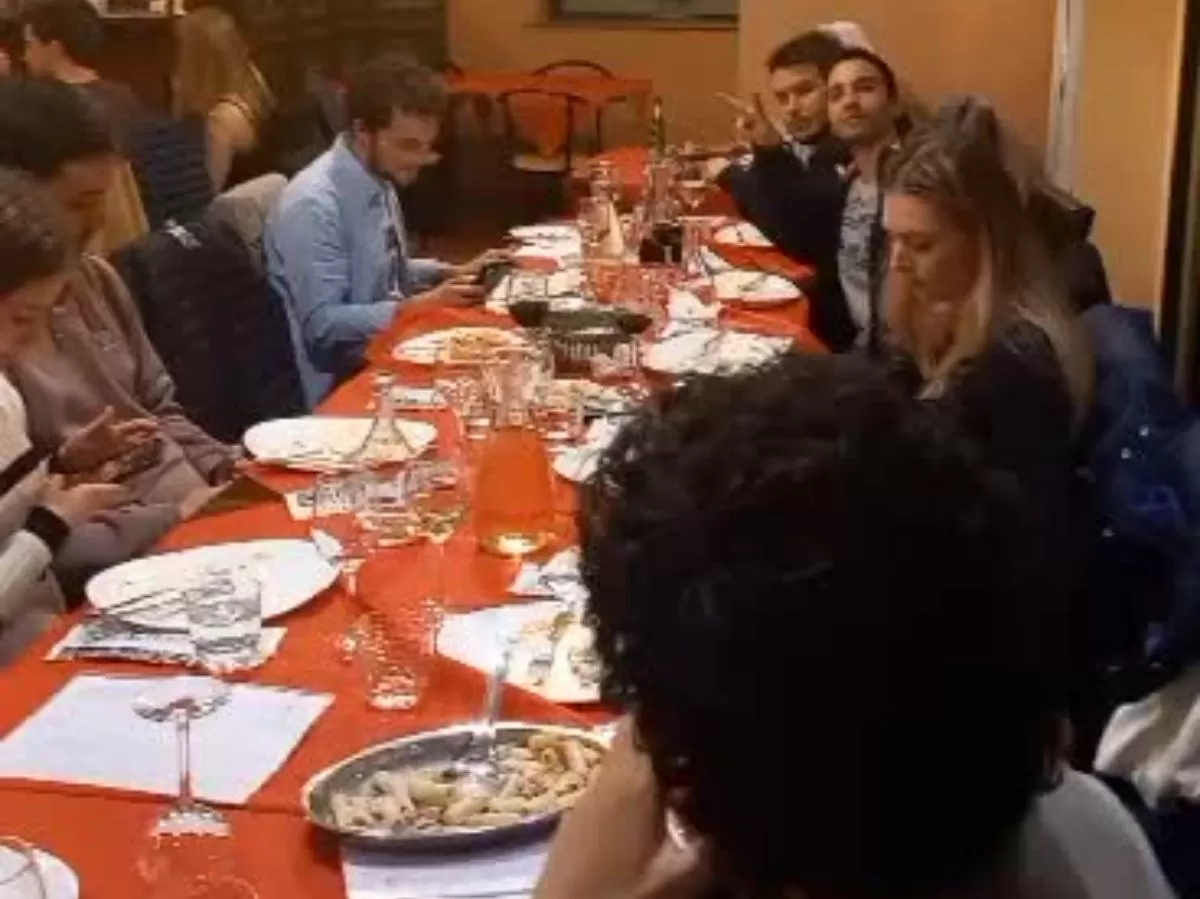 Group of people sitting at a table during pasta dinner.