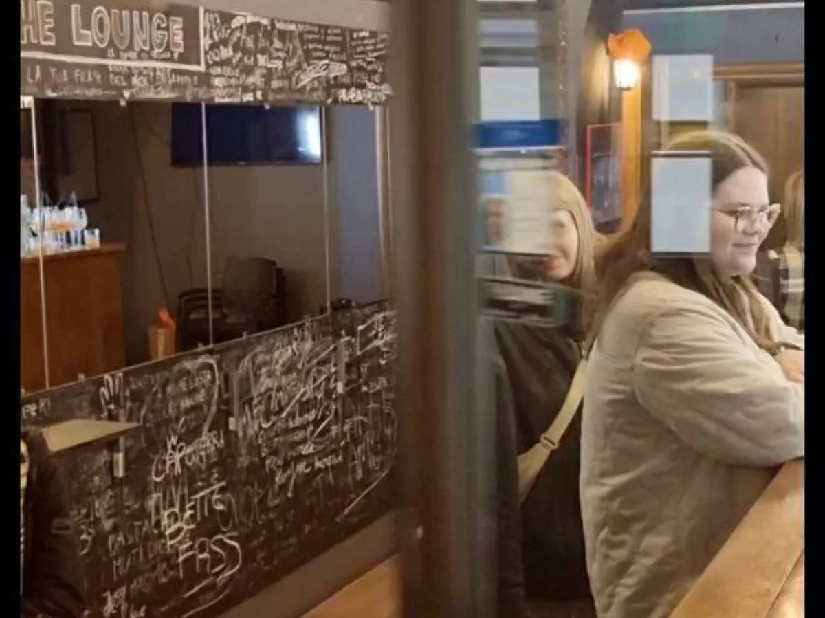 Girl ordering food at the local bar, standing behind the door.