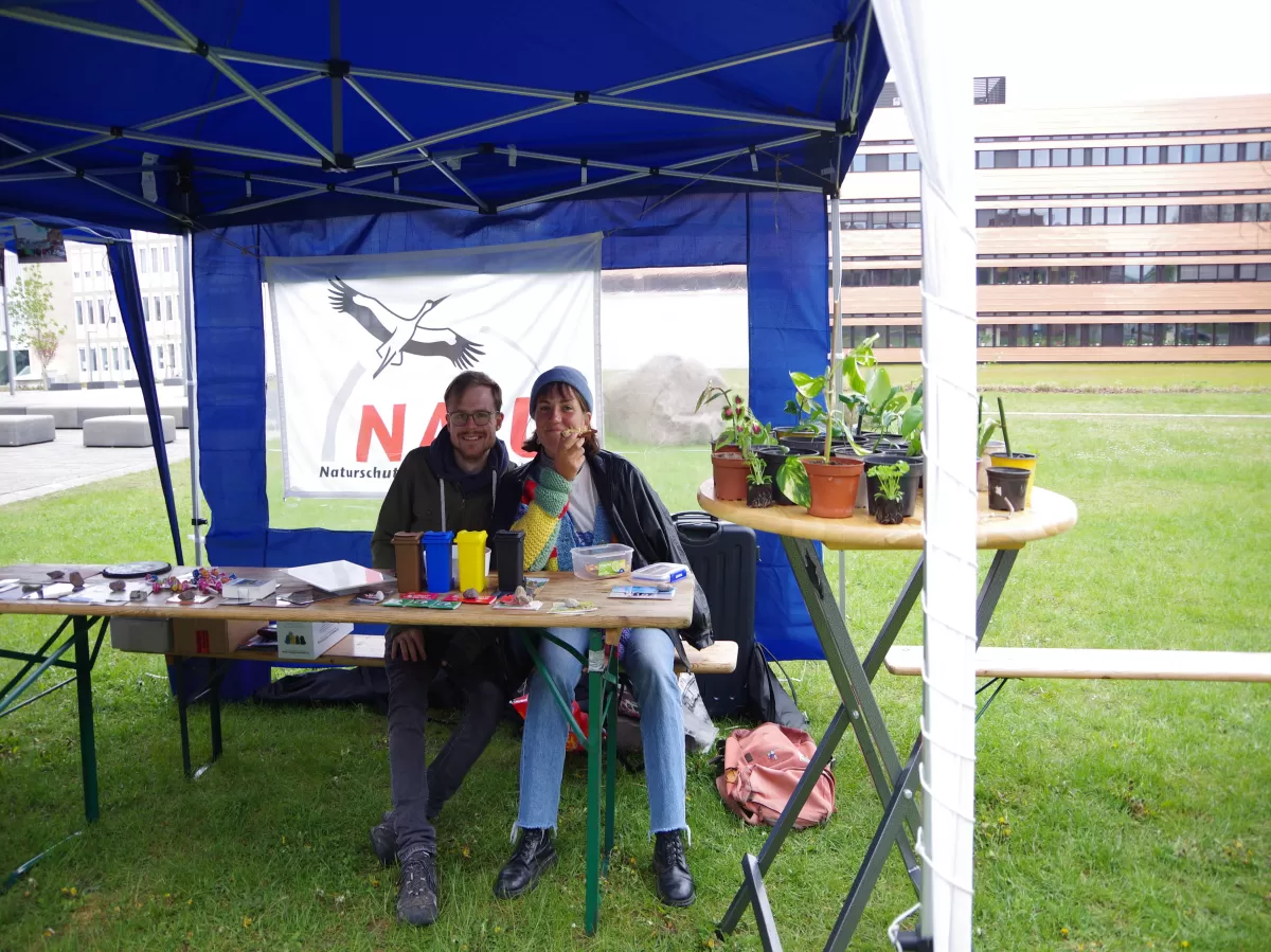 two students in their booth next to various plants