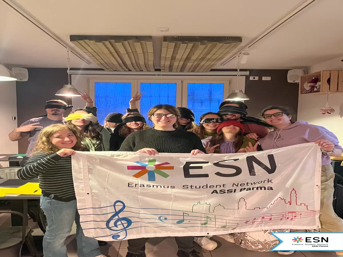 Participants smiling behind the ESN ASSI Parma flag.