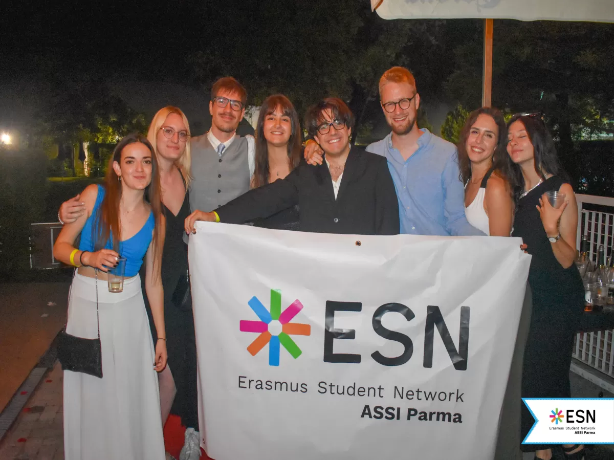 international students and a volunteer posing behind the ESN ASSI Parma flag.