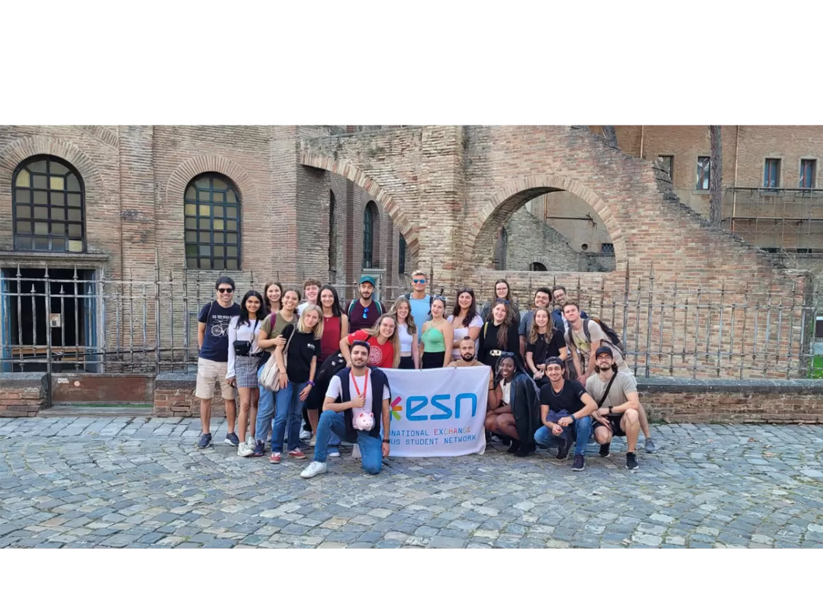 The ESNers are taking a group photo with the ESN flag in front of the Basilics of San Vitale