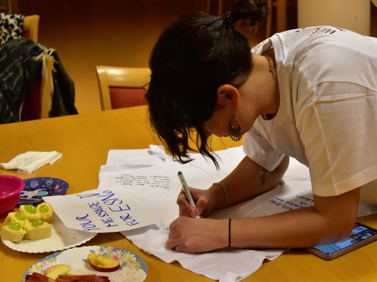 One of erasmus students writing a message on the ESN T-shirt