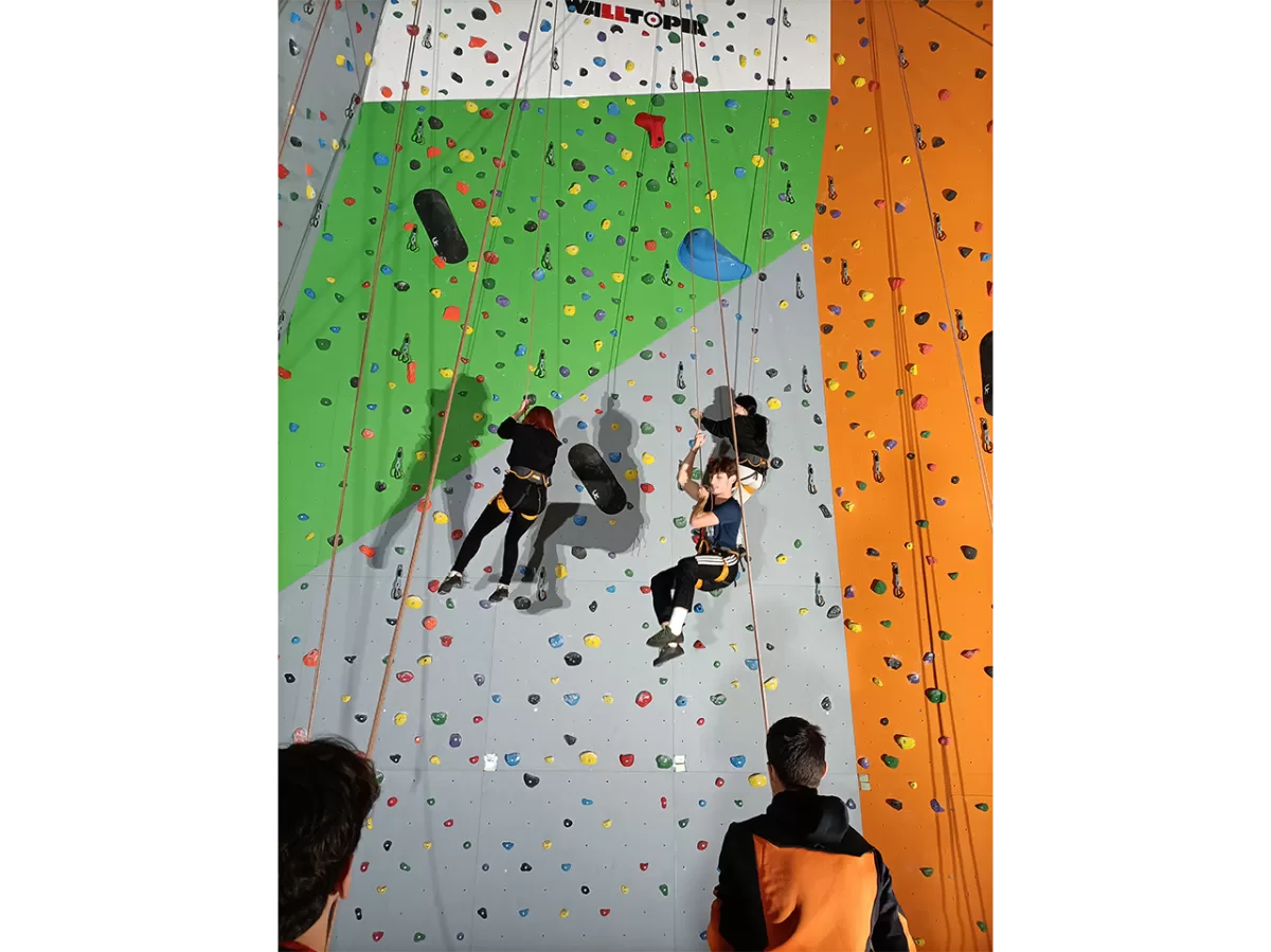 Two ESNers are coming down from the climbing wall hanging on  the ropes
