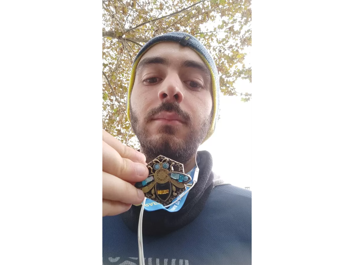 A staff member selfie at the end of the marathon holding his mosaic medal