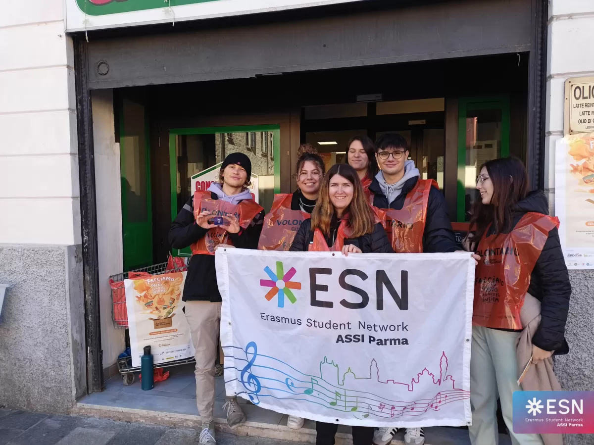 group of international students and volunteers smiling with the flag in front of the supermarket