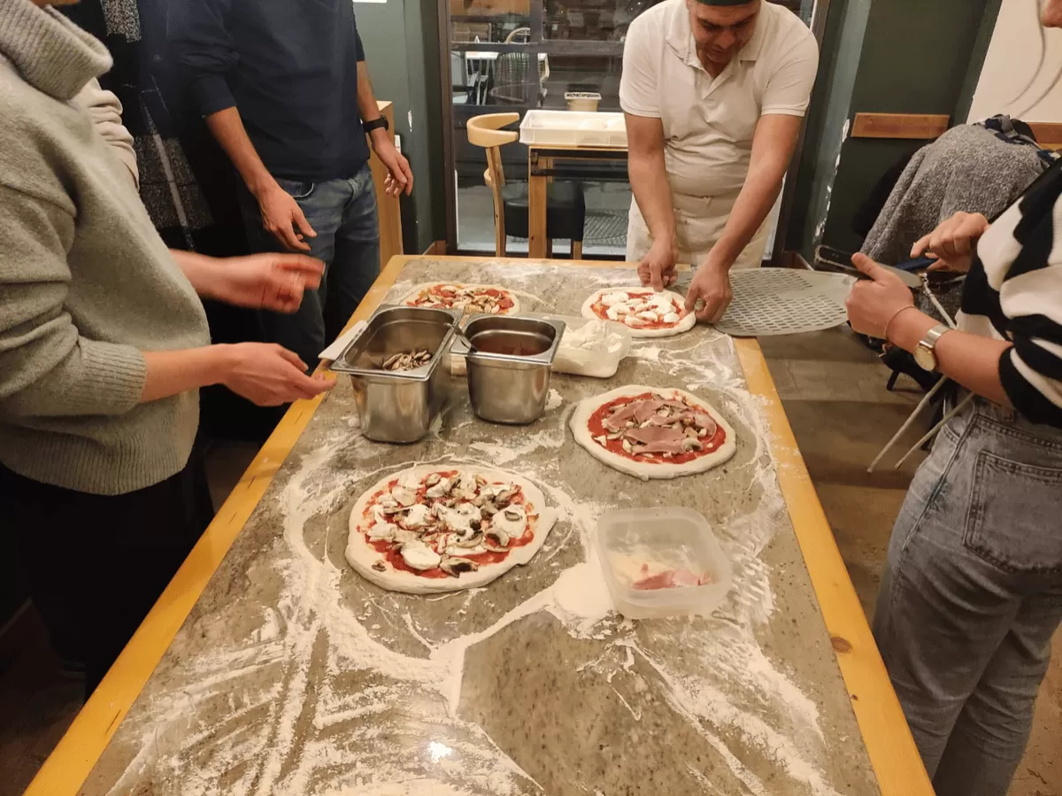 people putting toppings on pizza