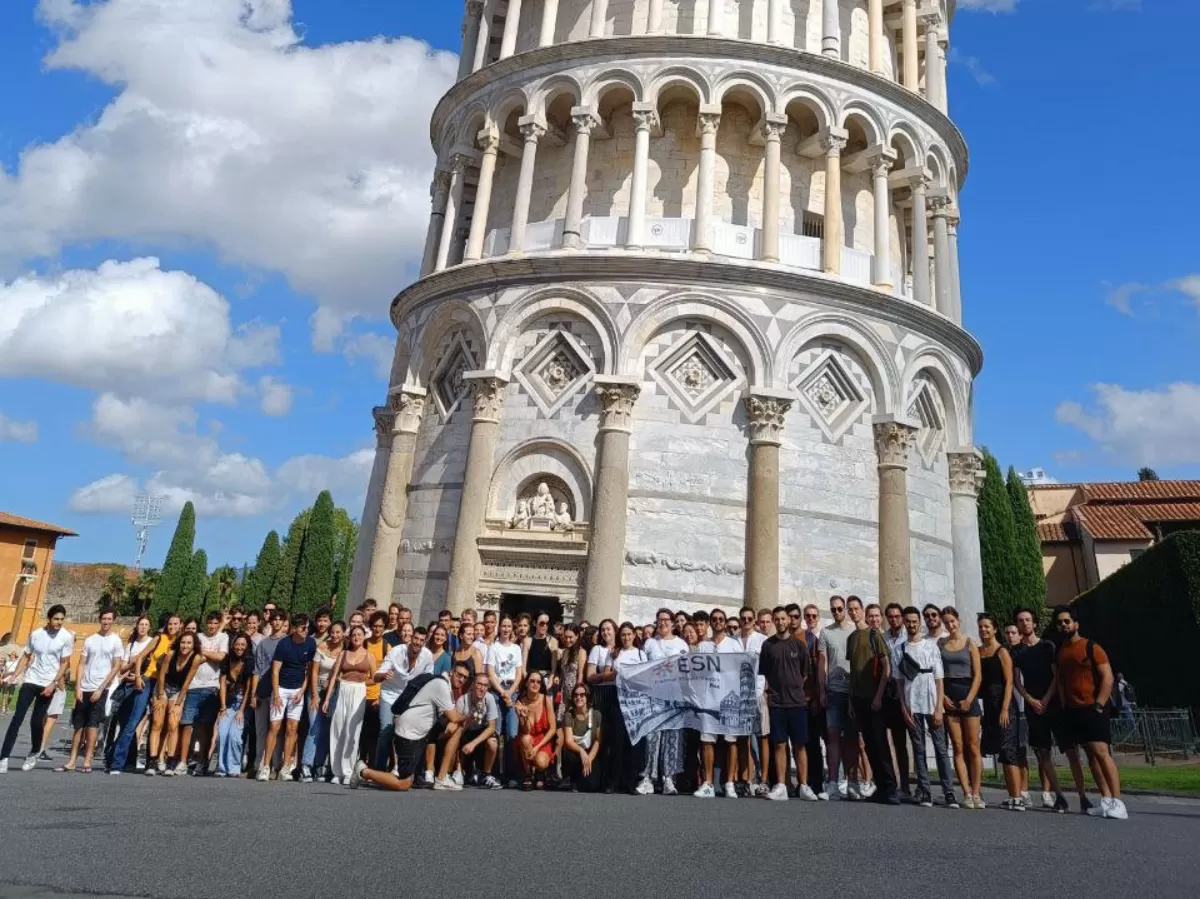 Group of people with Pisa Tower on the back and a flag of ESN Pisa.