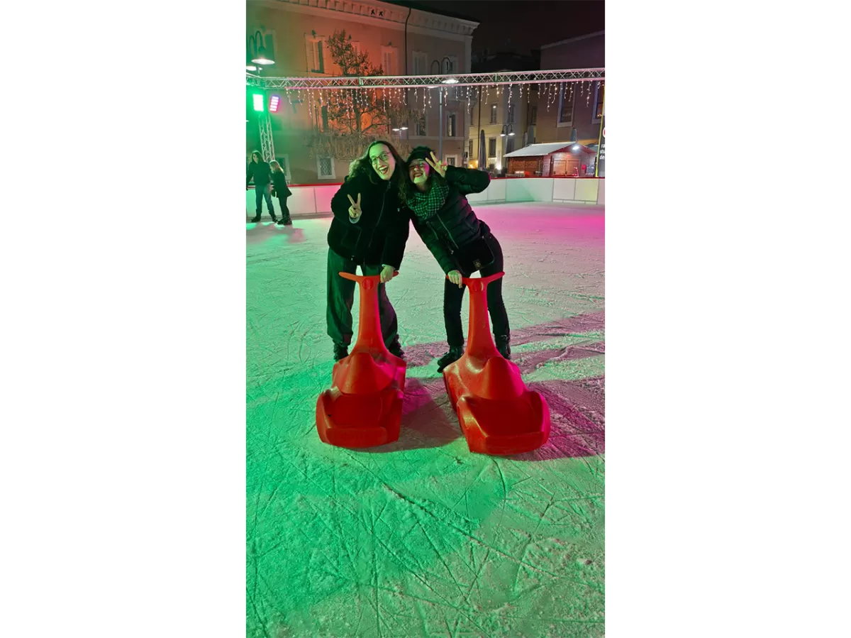 Two staff members ice skating with a support