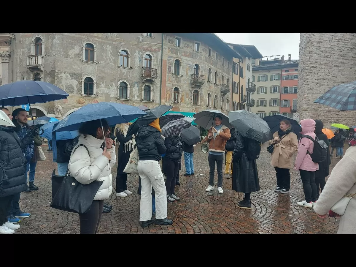 Group of students and volunteers under the rain learning about Trento
