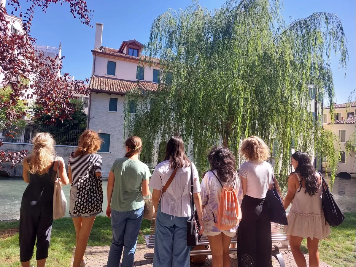 Group of students listing to the tour while standing near the river crossing Treviso
