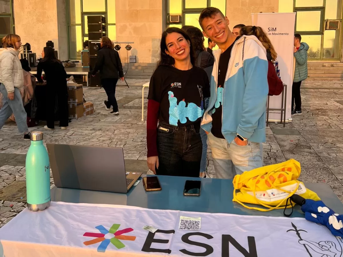 Two ESN volunteers are looking at the camera and smiling. They are standing behind the ESN table