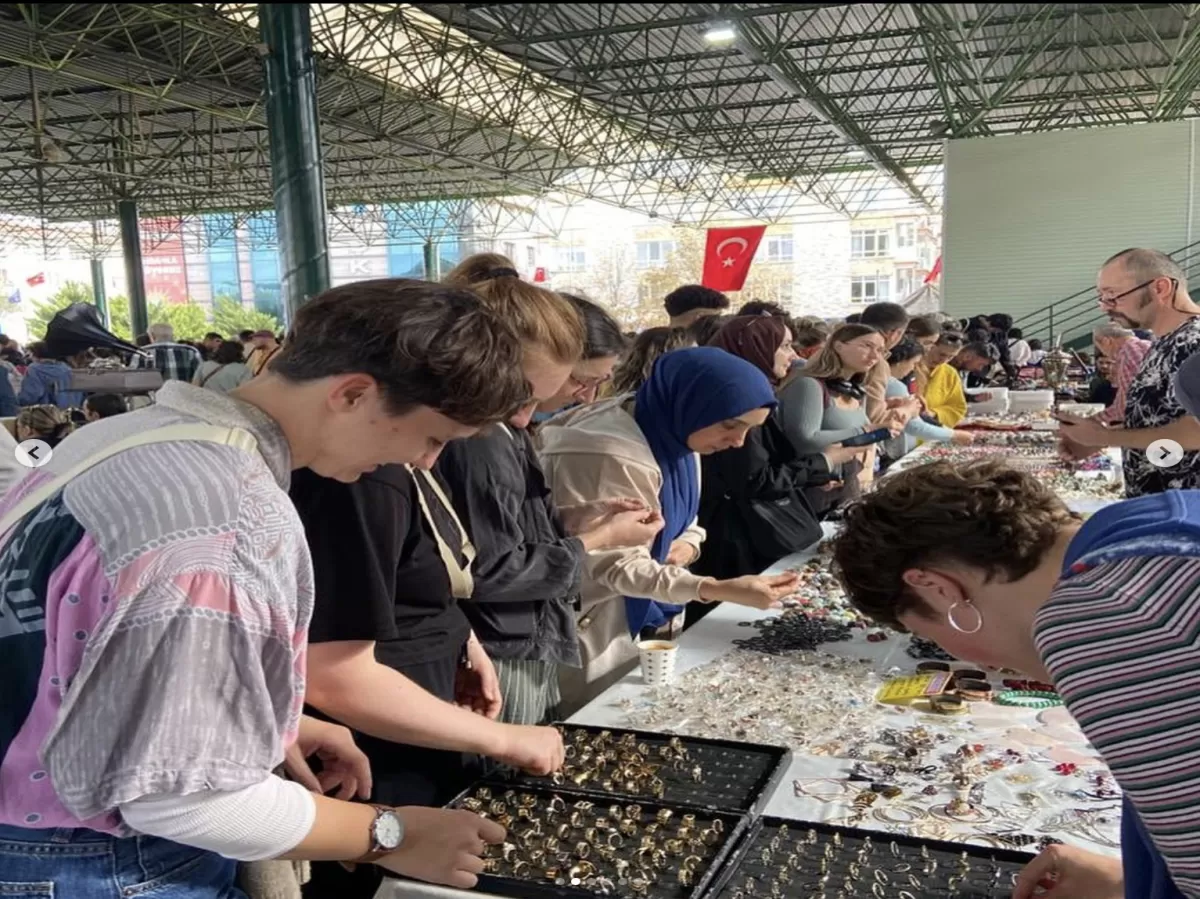 Erasmus Students looking over antique jewelry at the bazaar. There are some rings and bracelets on the table.