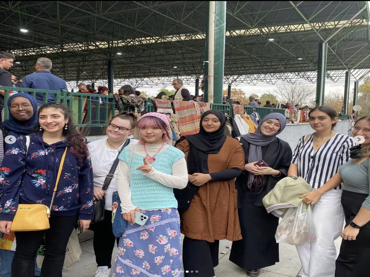 Photo of 8 Erasmus students posing and smiling in front of the bazaar.