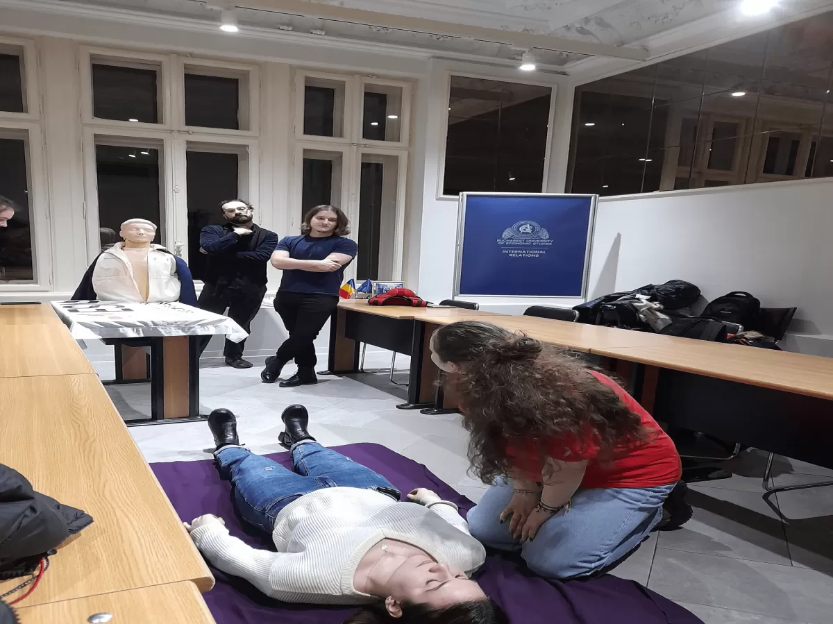 A first aid instructor demonstrating the safety position, a key technique for providing assistance during emergencies. The instructor is guiding participants in the proper posture, emphasizing safety and effective first aid practices.