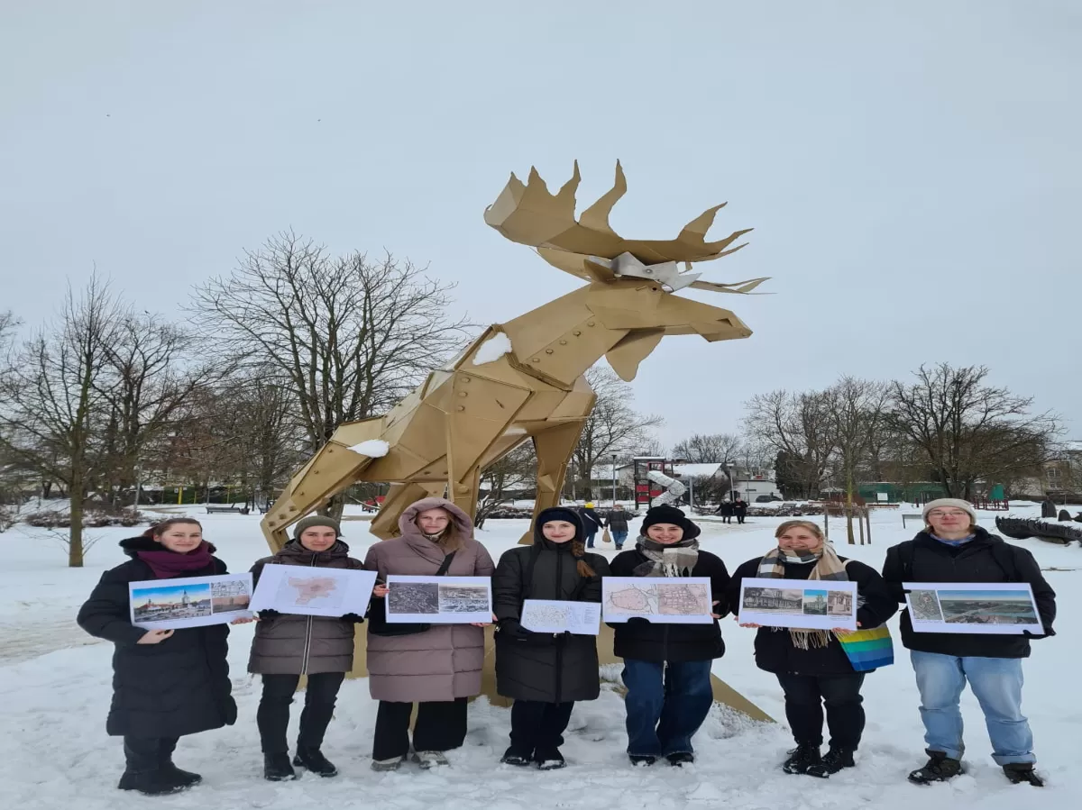small group of people in front of a moose monument holding picture cards