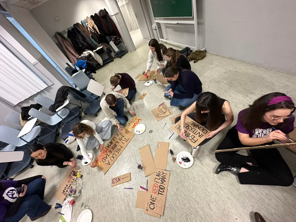 A group of people sitting on the floor painting banners for the Women's Day demostration