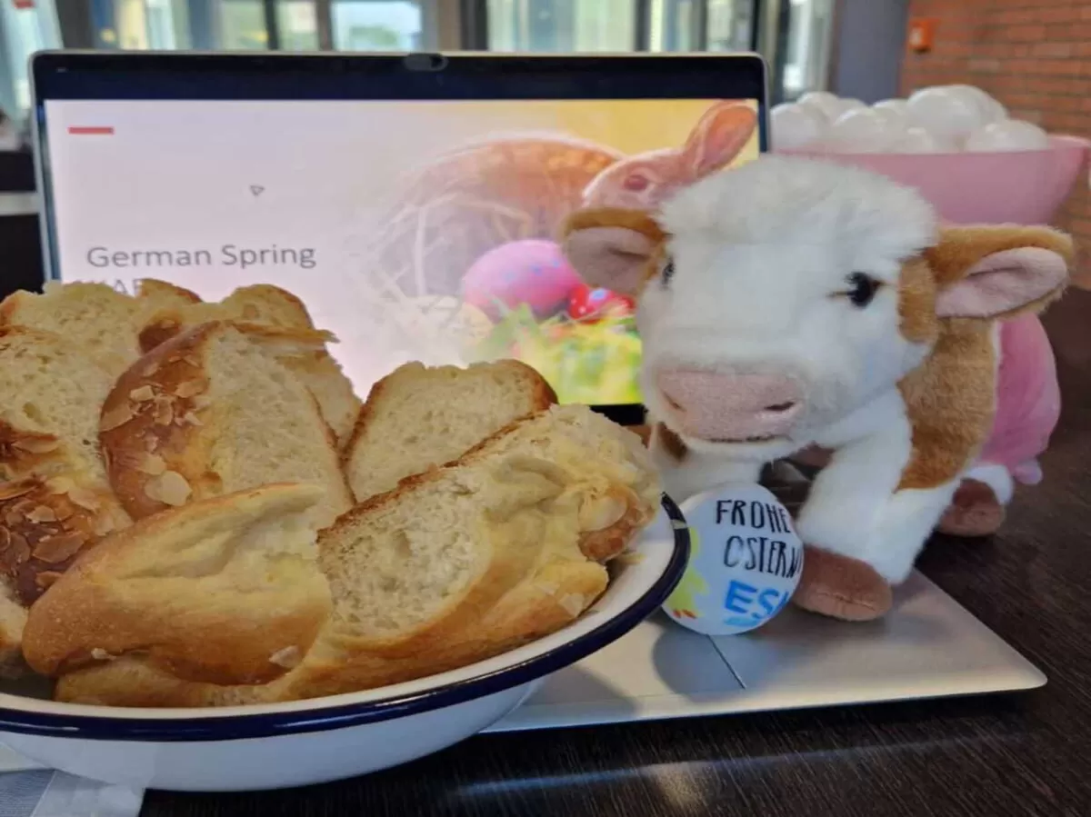 A cake and a cow plushie in front of a Laptop.