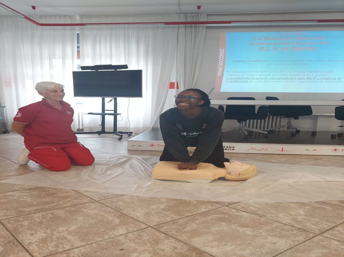 An ESNer implementing first aid on a mannequin while a woman from Red Cross observing