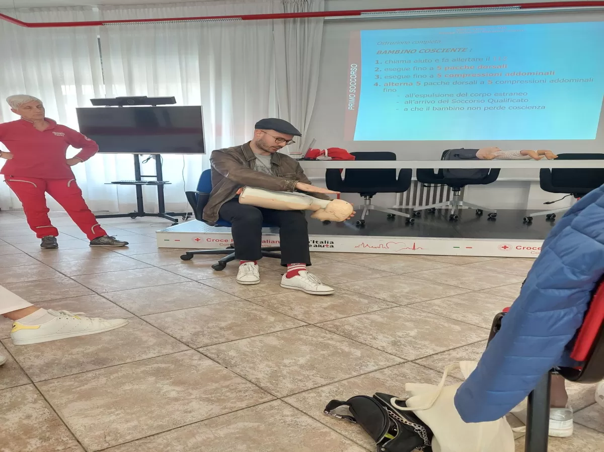 An ESNer implementing first aid on a mannequin while a woman from Red Cross observing