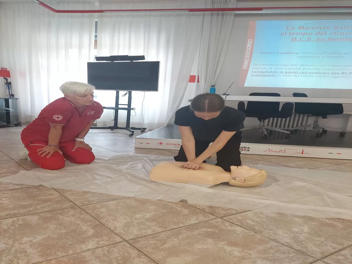 An Erasmus student implementing first aid on a mannequin while a woman from Red Cross observing