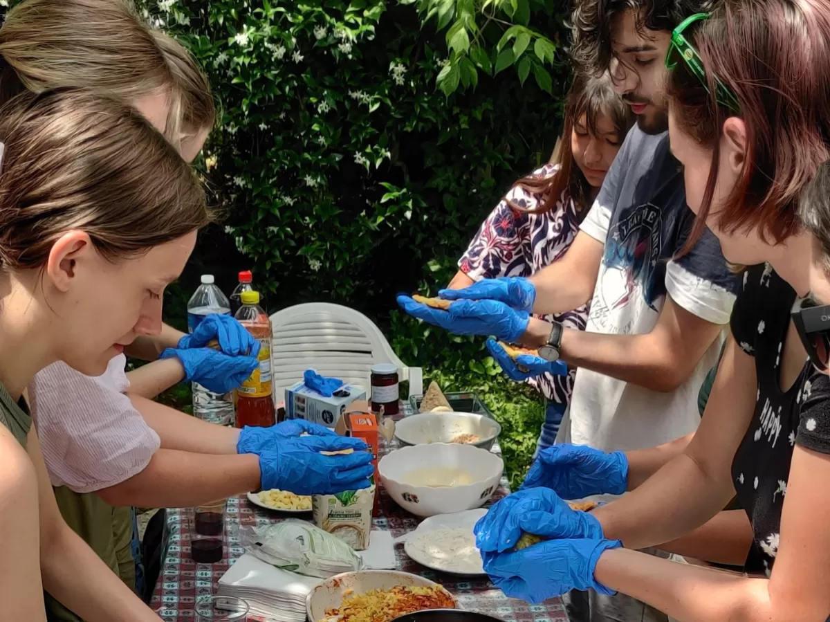 Erasmus students enthusiastically participate in making arancini, closely following Ruben's instructions. The hands-on cooking lesson allows them to experience the joy of crafting traditional Sicilian dishes and taste the fruits of their labor in a vibrant, communal setting.