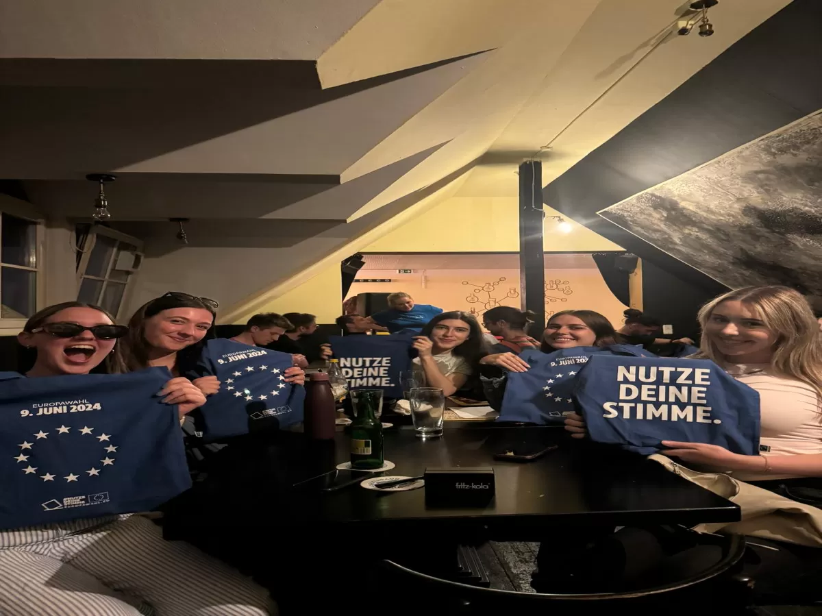 Group of students holding up blue bags with white letters saying "Nutze deine Stimme" and the EU Flag