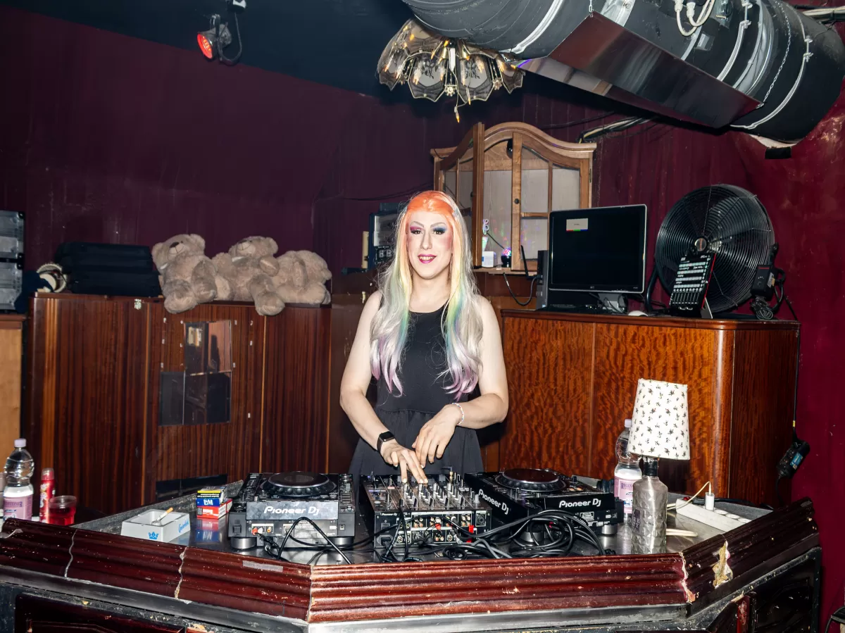 DJ at DJ pult with colorful hair and a smile