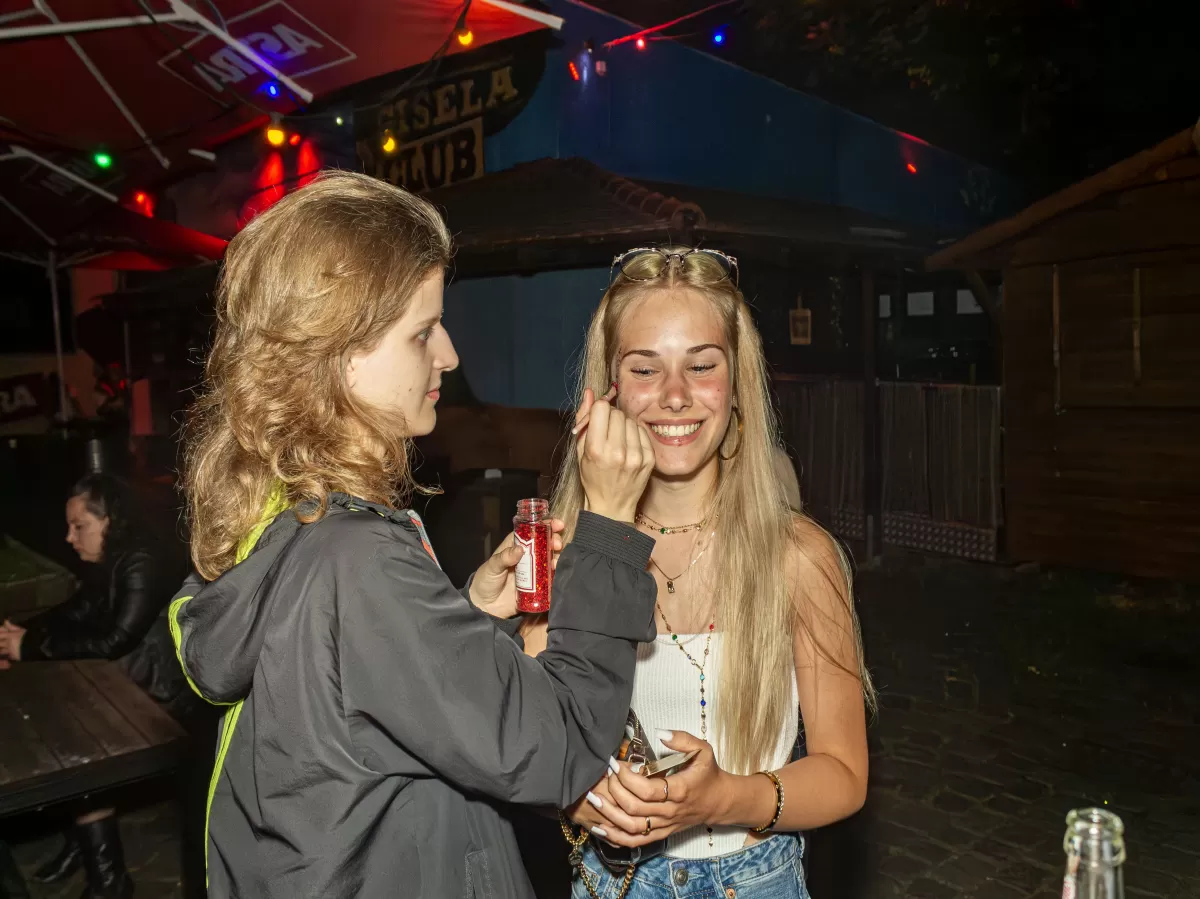 person putting red glitter on another persons face