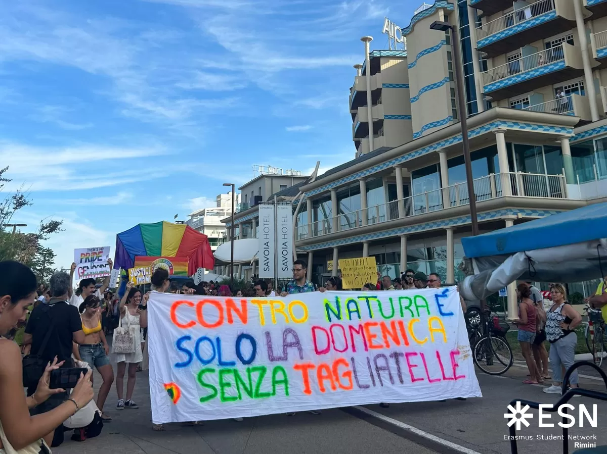 Group of people holding a big poster with a slogan in Italian "Contro natura è solo la domenica senza tagliatelle"