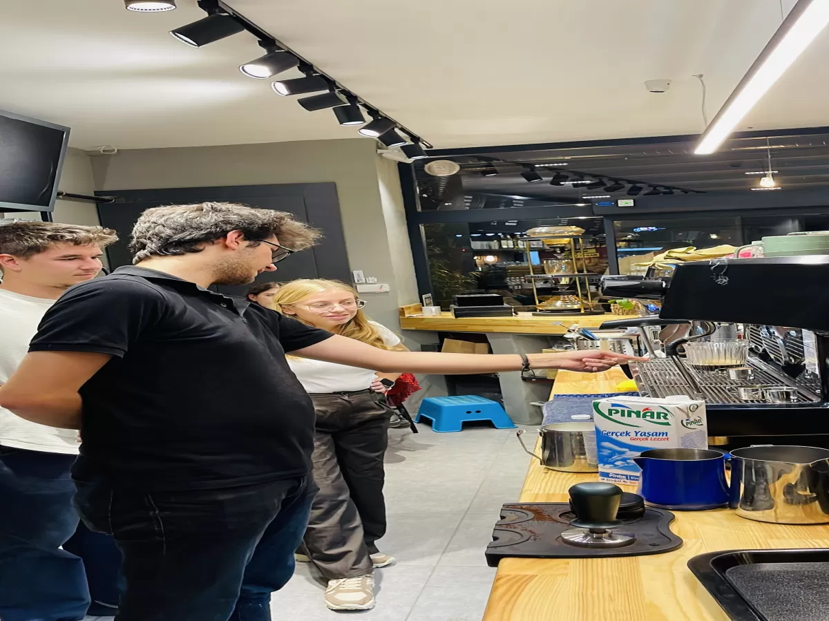Students with experienced barista, learning how a coffee machine functions.