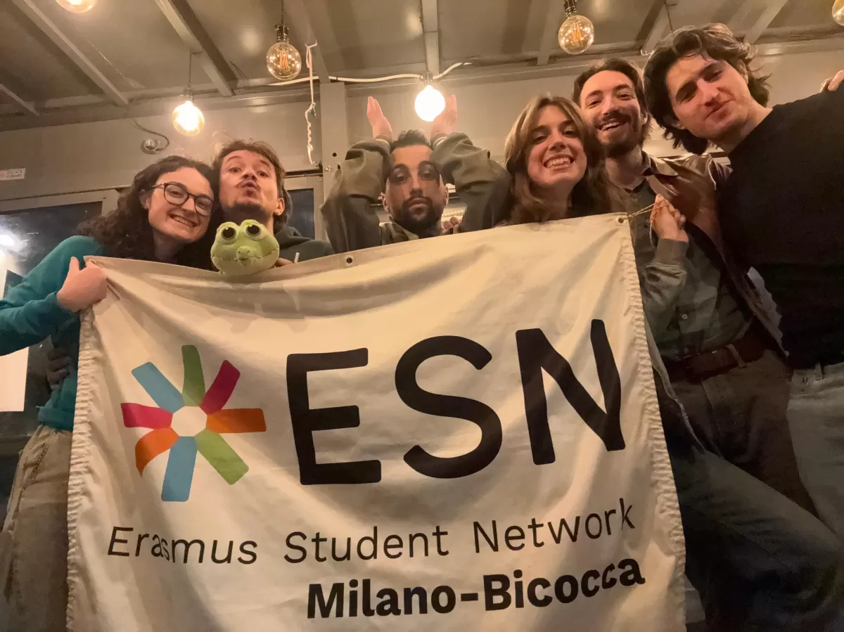 Volunteers and Cocco the crocodile holding ESN Milano-Bicocca flag