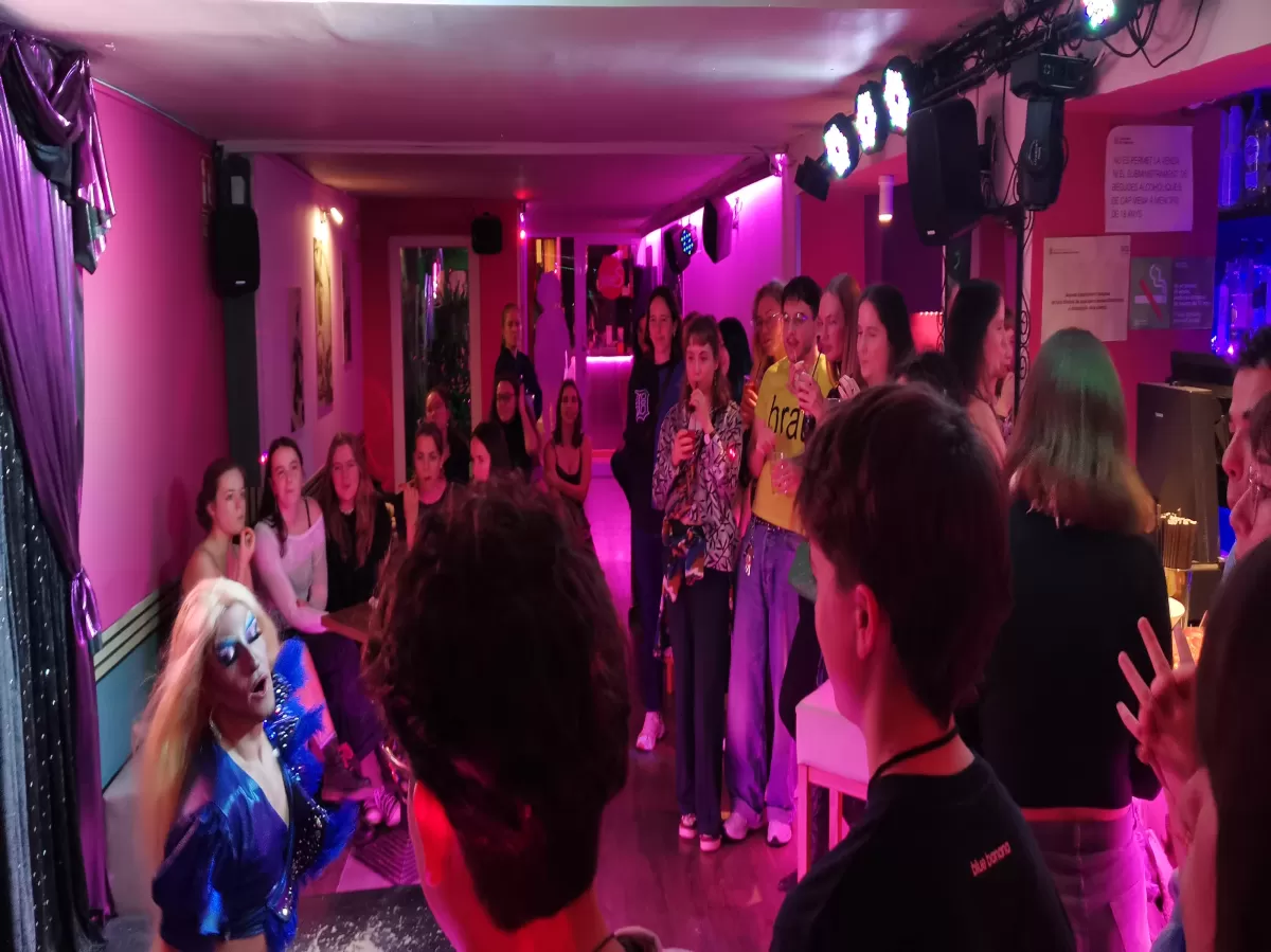 Group of people enjoying the performance of a drag queen indoors