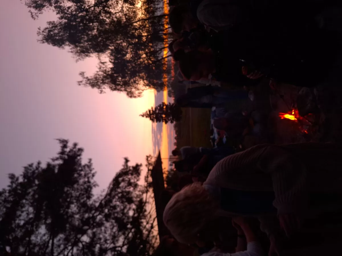 participants by a bonfire in the evening with sun set in the background