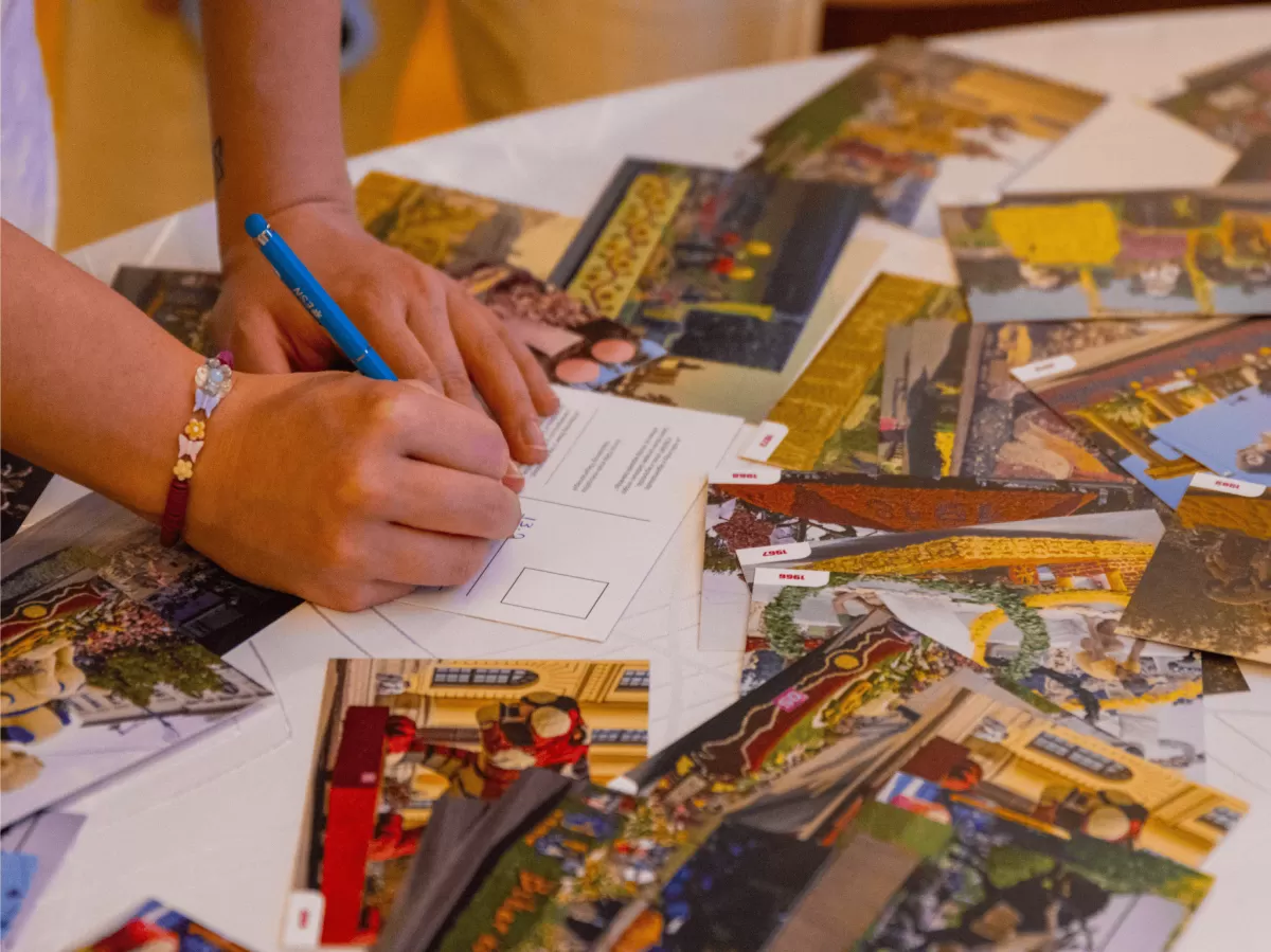 Postcards about the famous sights of Debrecen on a table, getting signed by international students