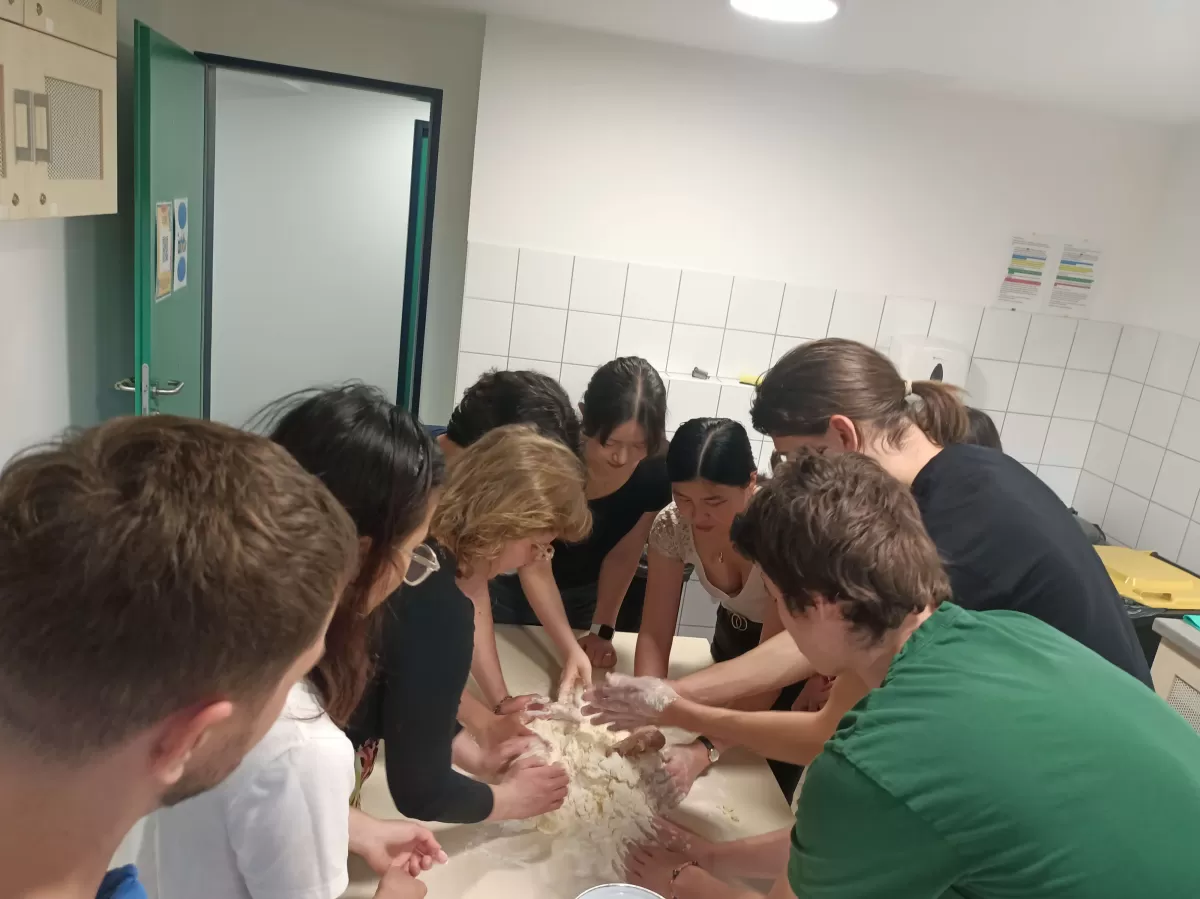 a group of people making dough together around a table