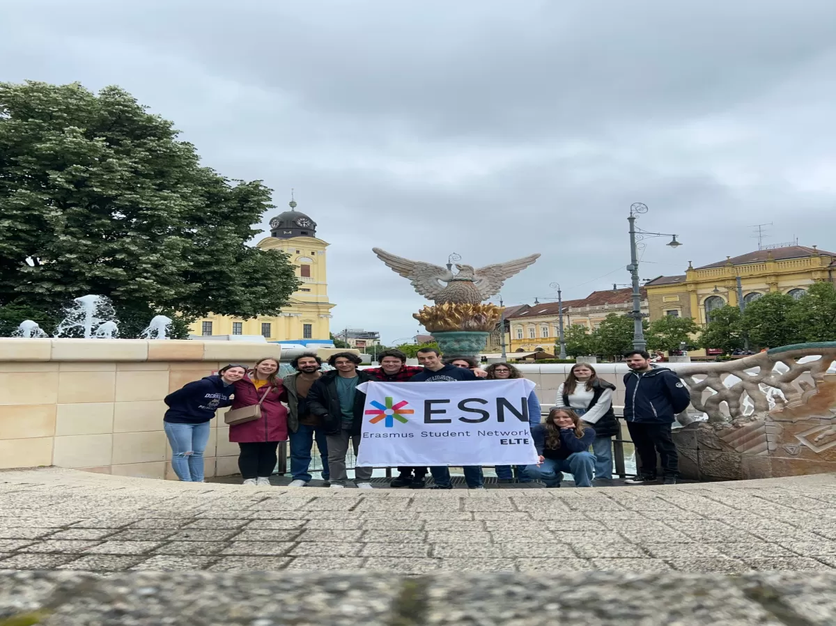 a group picture next to the fountain at the main square of Debrecen with an ESN ELTE flag