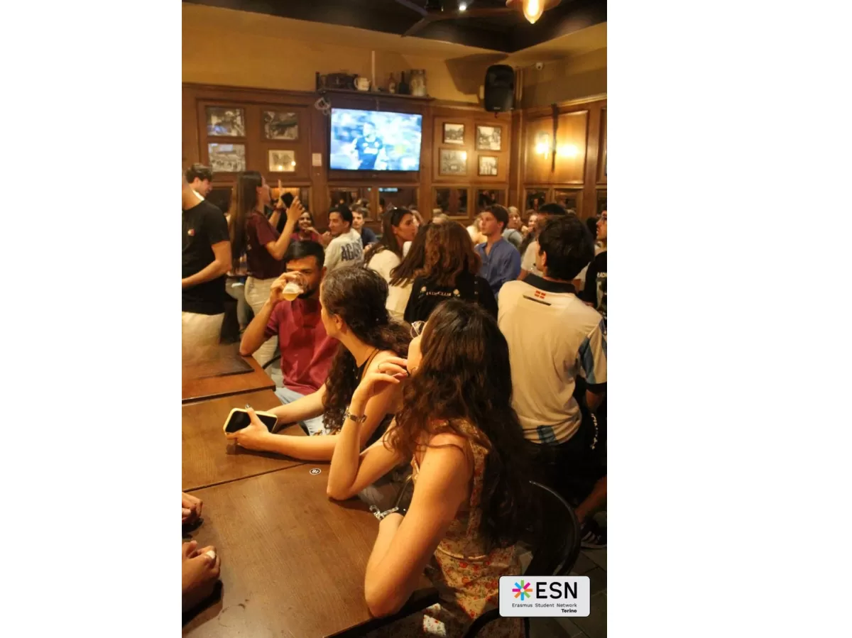 Group of people chatting in a "speed date" vibe while looking at a football match.