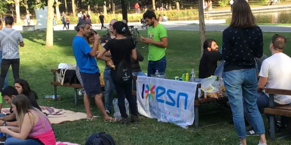 The students are sitting in the park and playing cards during the picnic part of the event.