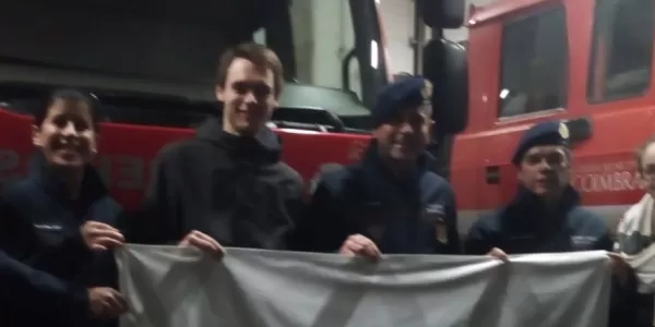 Students and firefighters holding a flag and smiling.