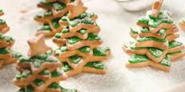 A picture with christmas biscuit in the shape of christmas trees with a tiny biscuit star at the top
