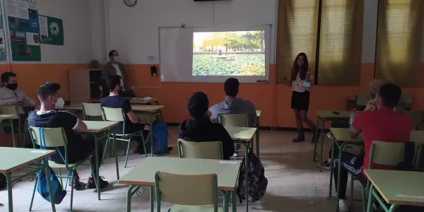 An Erasmus student is doing a presentation on her country to a classroom full of students.
