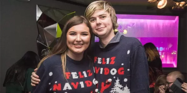 Two students wearing Christmas Sweatshirts, posing next to each other. 