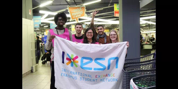 Volunteers and International students of ESN Strasbourg holding the ESN Flag in front of the supermarket where they collected food