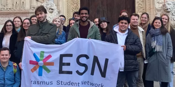 International students posing with the Flag of ESN Modena in front of the Cathedral of the city of Modena