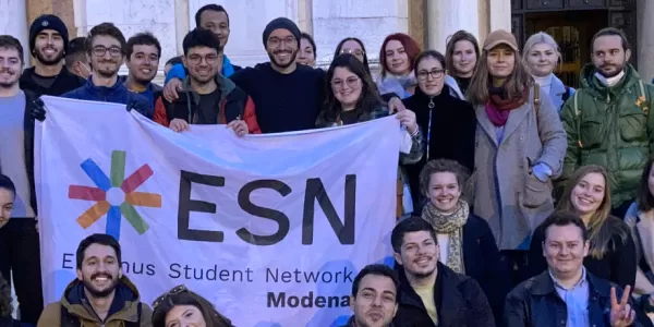 International students posing with the Flag of ESN Modena in front of the Cathedral of the city of Reggio Emilia