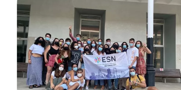 Group of students looking at the camera (with masks on) and with an ESN Barcelona UPF flag.