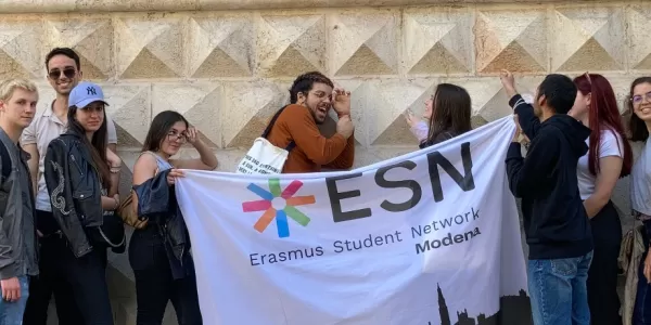group of international students posing with the ESN Modena flag in front of Diamanti Palace in Ferrara