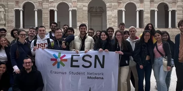 group of international students posing with the ESN Modena flag in Chiostri di San Petro in Reggio Emilia