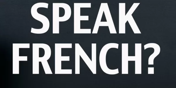 Board indicating "Speak French?" with a cup of coffee and sticky notes